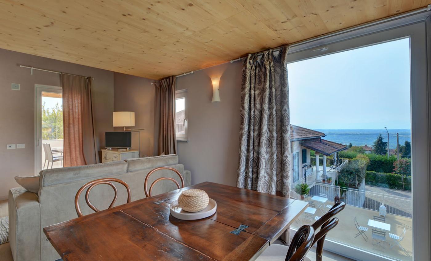 Soggiorno luminoso con vista lago, arredamento elegante e tavolo in legno.