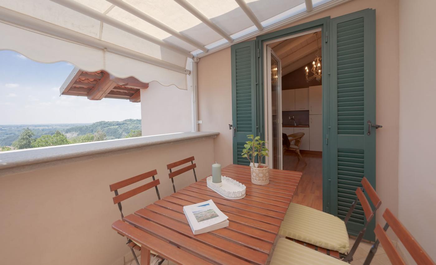 Terrazza accogliente con tavolo in legno, vista panoramica e accesso alla cucina.